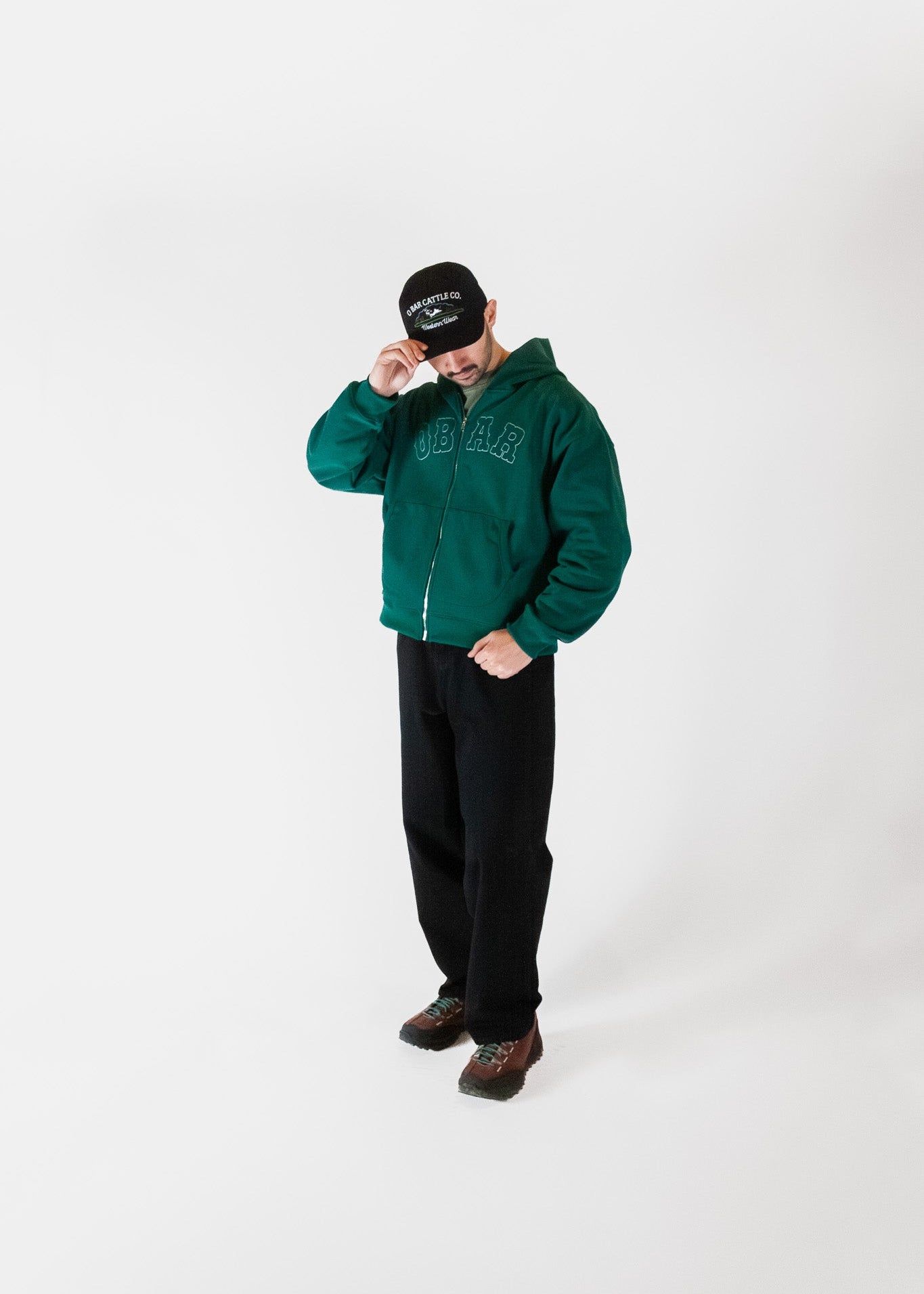 Person wearing a green jacket and black pants on a white background