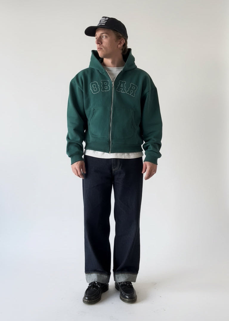 Person wearing a green hoodie with 'OBAR' branding on a white background